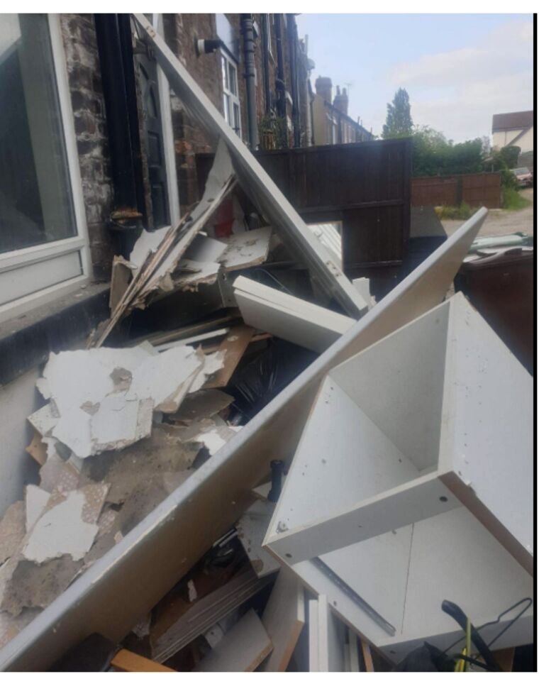 Plasterboard, old kitchen units and timber piled outside a back door